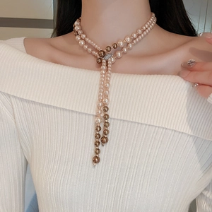 Detail of layered long necklace with champagne pink and brown pearls and crystal clasp