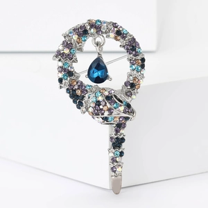 Macro detail of silver snake brooch featuring multi-color rhinestones and blue drop gemstone