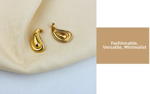 Detailed macro view of 18K gold plated tiered drop earrings on beige silk fabric