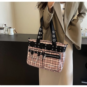 Detail of pink plaid tote bag with black eyelet straps and metal chain accents