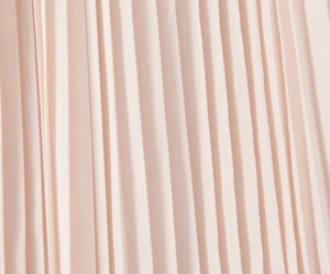 Macro shot of pink pleated fabric detail showing smooth vertical textures on the dress