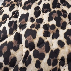 Detailed macro view of quilted leopard print fabric with precise curved stitching texture