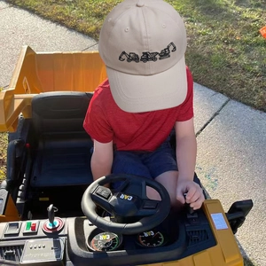 Kids khaki cotton baseball cap with excavator embroidery worn by a child in a toy car