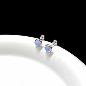 Macro shot of silver titanium steel earrings with iridescent blue moonstones on ceramic