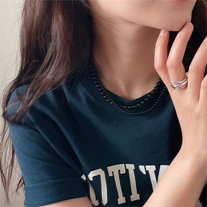 Detail of silver interlocking rings and black bead necklace worn by a fashion model