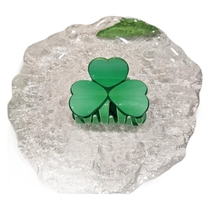 Green acrylic clover hair claw clip displayed on a decorative glass tray with white background