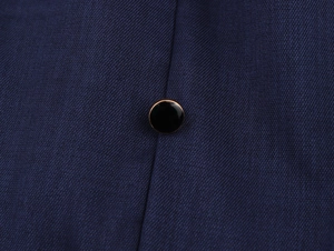 Dettaglio ravvicinato del tessuto twill blu navy e bottone decorativo bordato d'oro