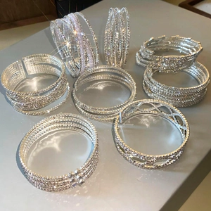 Detailopname van zilveren crossover armbanden met strassteentjes en parel accenten