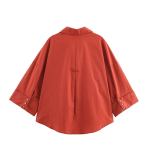 Detailed back view of a burnt orange poplin shirt with batwing sleeves and pleated design