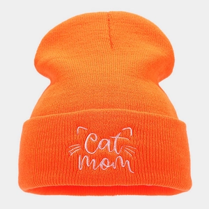 Detailed close-up of Cat Mom white embroidery on an orange ribbed knit beanie hat