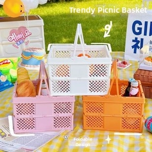 Close-up of foldable mesh picnic baskets in pink, white, and orange on a grass lawn