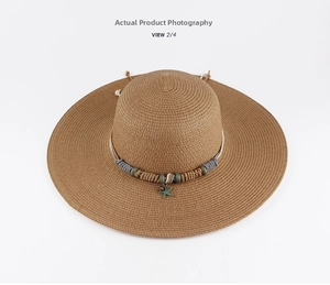 Detail of wide brim straw sun hat with bohemian starfish pendant and braided rope band