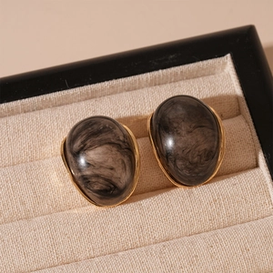 Detail of vintage marble pattern resin earrings with golden metal edges in jewelry box