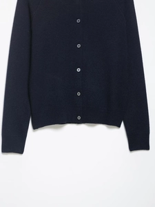 Detailed close-up of dark blue knit cardigan with round buttons and ribbed cuffs on white