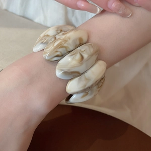 Close-up of marble patterned acrylic stretch bracelet with amber texture on model's wrist