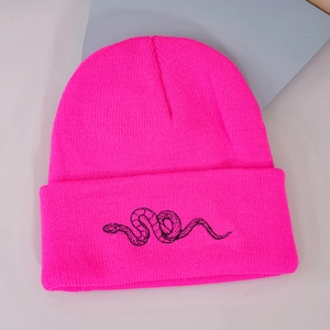 Close-up of fluorescent pink knit beanie with black snake embroidery on the folded cuff