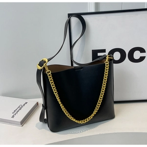 Detail of black leather bucket bag with thick gold chain handle and shoulder strap