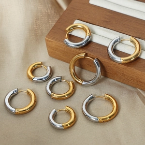 Minimalist two-tone circular earrings set in gold and silver finish on silk background