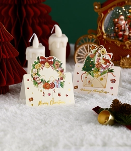 Close-up of gold-stamped Merry Christmas cards featuring festive wreath and gift designs