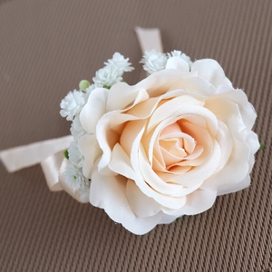 Elegant cream rose boutonniere with silk ribbon and white floral accents for wedding events