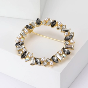 Close-up of sparkling crystal wreath brooch with pearls on a golden metal base