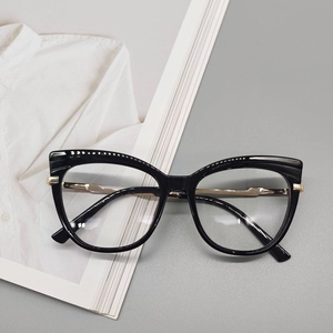 Dettaglio degli occhiali cat-eye neri con accenti metallici dorati su una rivista