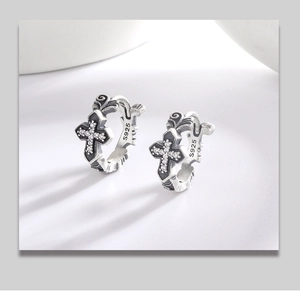 Macro detail of S925 sterling silver hoop earrings with vintage cross and crystal pavé