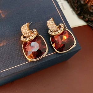 Macro view of vintage gold C-shaped earrings with red gemstone and pavé rhinestones