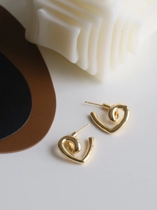 Close-up of elegant gold heart-shaped stud earrings with twisted metal texture