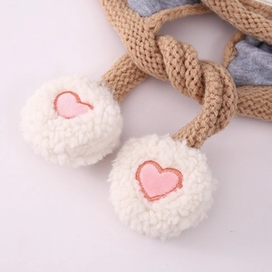 Détail de maille d'un bonnet d'hiver avec pompons doux et broderie de cœur rose