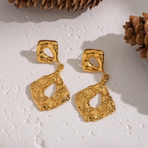 Detailed view of golden irregular geometric earrings with hammered metal texture