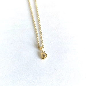 Macro shot of minimalist gold initial D pendant necklace with classic O-chain on white