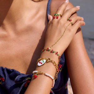 Detailed view of cherry enamel ring and strawberry pearl bracelet on model hand