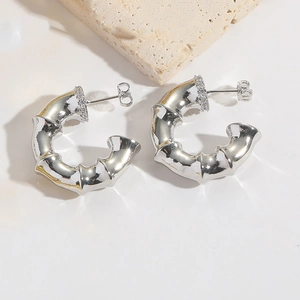 Detailed close-up of silver C-shaped bamboo texture hoop earrings with crystal pavé accents