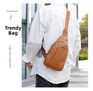 Outdoor view of a brown faux leather crossbody bag with adjustable strap and headphone port
