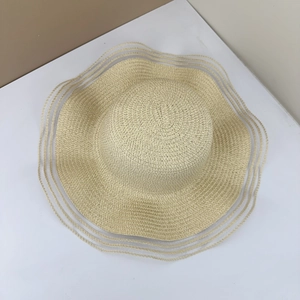 Detail of a beige straw sun hat featuring wavy edges and layered translucent mesh trim