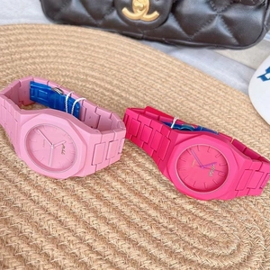 Close-up of light and dark pink silicone quartz watches on a rustic woven mat surface
