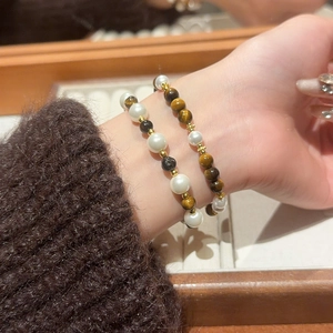 Detail of layered bracelet set with tiger eye stones, pearls and golden cross beads