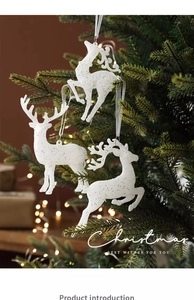 Trois rennes pailletés blancs suspendus à un sapin de Noël avec des lumières chaudes