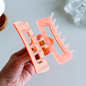 Pink square cutout hair claw clip with metal spring for women on a light background