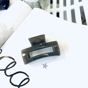 Detail of a dark gray translucent square hair claw clip with a glossy acrylic finish