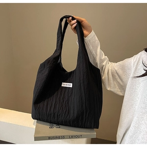 Details der schwarzen Nylon-Tasche mit Faltenstruktur und weißem Kiss Yourself-Etikett