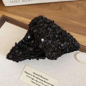 Detail of triangular acrylic hair claw clip with black sequins and velvet texture