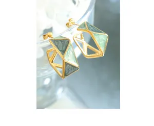 Detailed macro shot of geometric gold earrings with green marble enamel inlay and metal texture