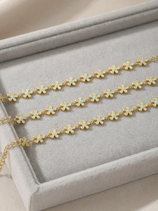 Detailed macro of gold flower chain bracelet with light blue enamel and lobster clasp closure