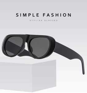 Detail view of oval black fashion sunglasses on a minimalist white stone display