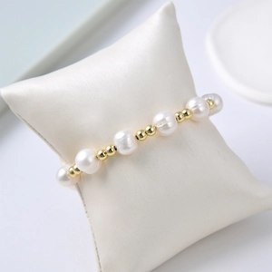 Elegant gold-plated pig nose chain bracelet with freshwater pearls on a white pillow