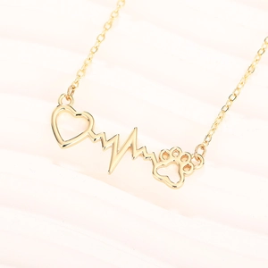 Detailed close-up of golden necklace featuring heart, EKG wave, and pet paw print pendant