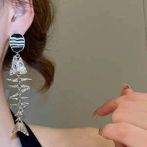 Detail shot of long silver fishbone earrings with black and white striped round studs