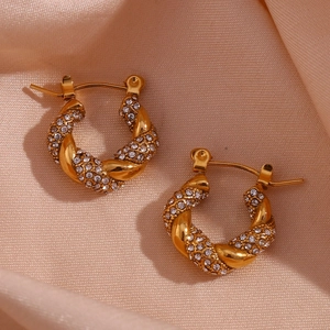 Detail of 18K gold plated twist hoop earrings with pavé zircon stones on silk background